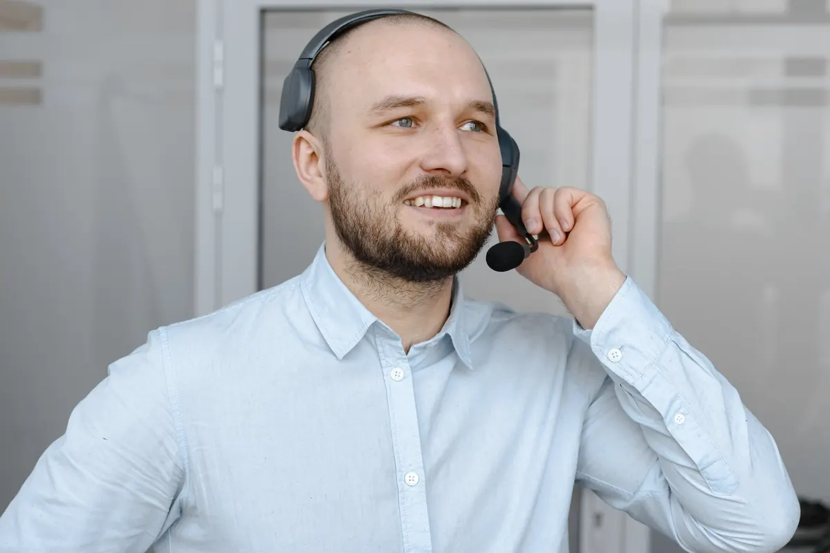 Smiling customer support agent wearing a headset at his desk