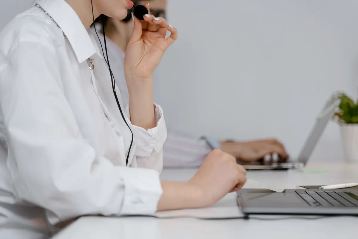 Customer support agent talking on a headset while typing on a laptop