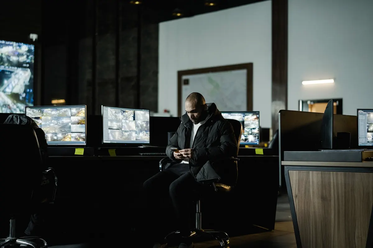 Analyst in a dark control room watching multiple monitors
