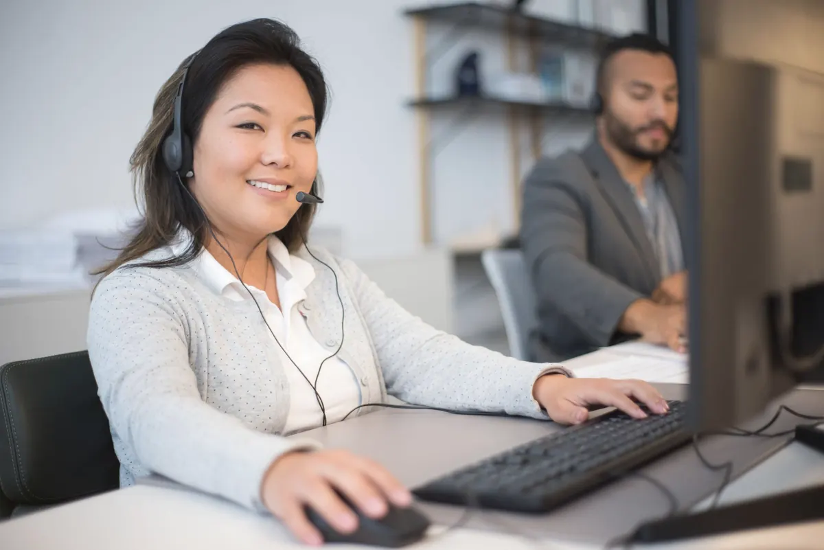 Dispatcher with a headset working at a computer in an office