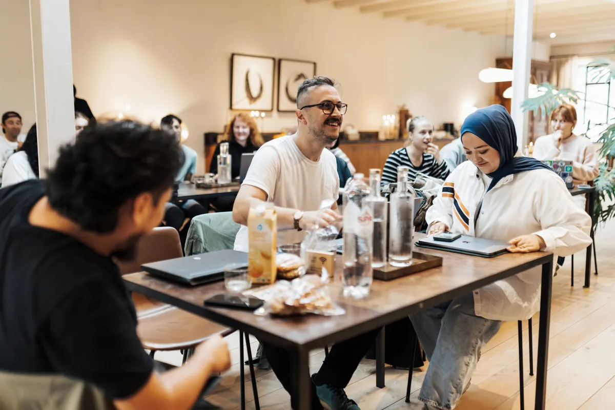 Team of people working at a long table with laptops